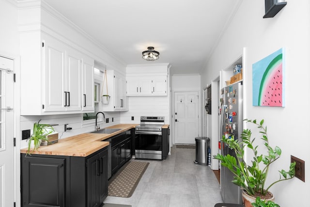 kitchen with white cabinets, a sink, butcher block countertops, and appliances with stainless steel finishes