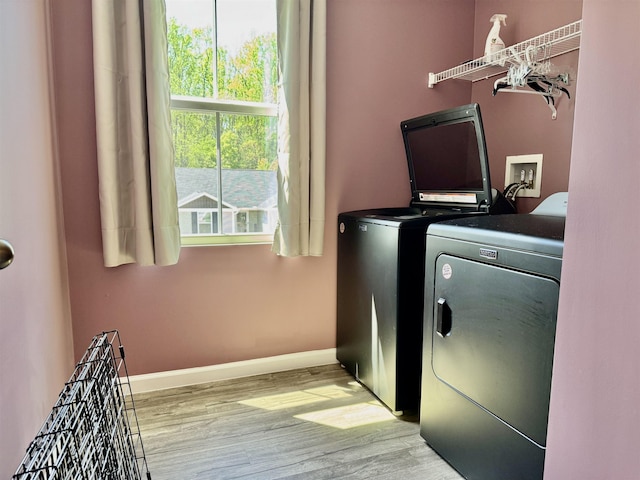 clothes washing area with washer and clothes dryer, light wood-type flooring, laundry area, and baseboards