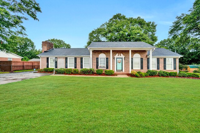 ranch-style house with a front yard, brick siding, fence, and a chimney