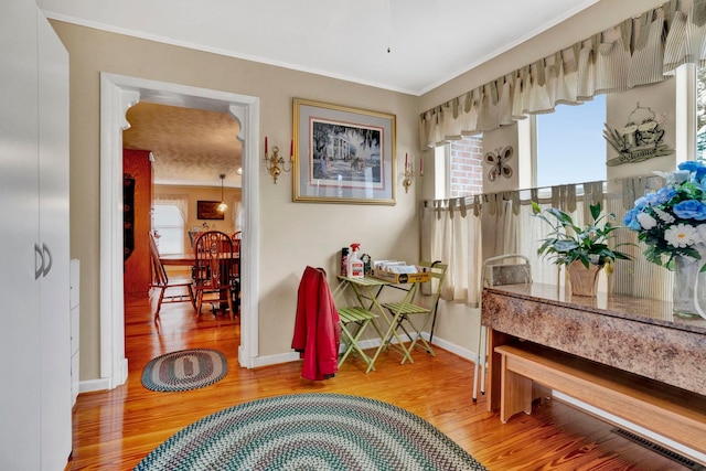 living area with light wood-style flooring, ornamental molding, and a healthy amount of sunlight