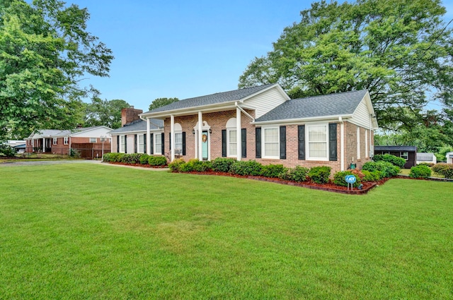greek revival inspired property featuring brick siding, a front yard, and a shingled roof