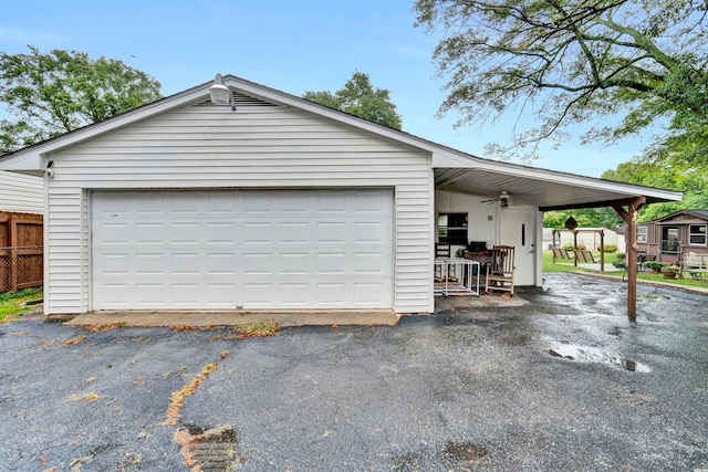 garage featuring a detached garage, ceiling fan, and fence
