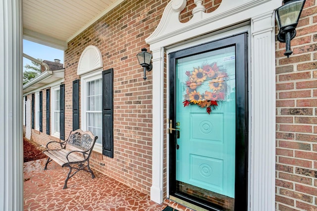 doorway to property with brick siding and covered porch