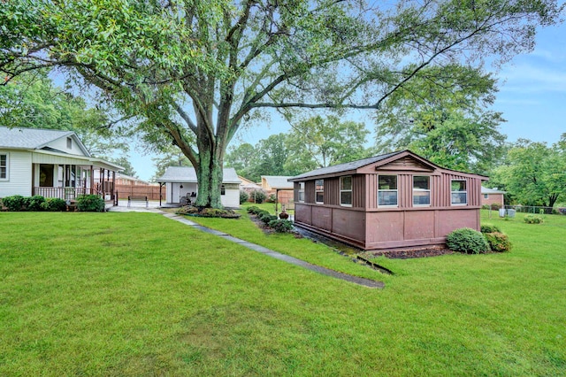 view of yard featuring a porch, an outbuilding, and fence