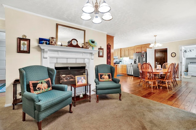 living area featuring ornamental molding, wood finished floors, an inviting chandelier, and a tile fireplace