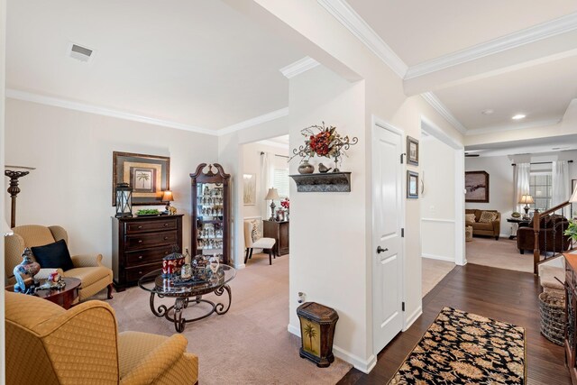 living area featuring wood finished floors, baseboards, ornamental molding, and visible vents