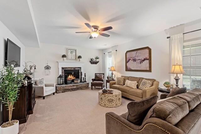 living room with light carpet, a fireplace, and a ceiling fan