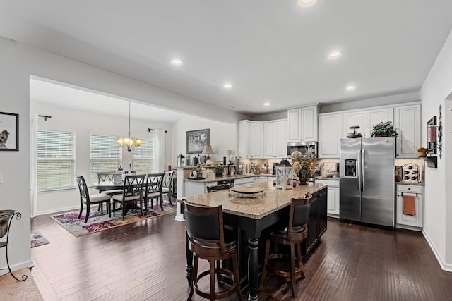 kitchen with light stone countertops, dark wood-type flooring, white cabinetry, a center island, and stainless steel appliances