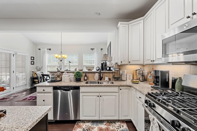 kitchen with backsplash, a chandelier, appliances with stainless steel finishes, a sink, and dark wood-style floors