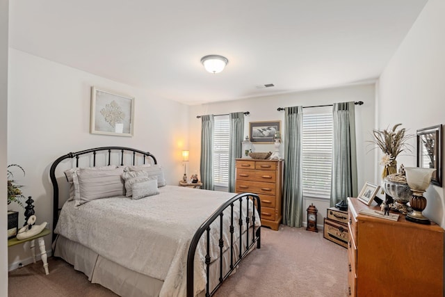 bedroom with visible vents, baseboards, and light carpet