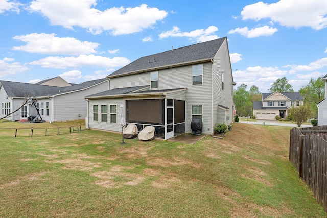 rear view of house featuring fence private yard, a sunroom, and a lawn