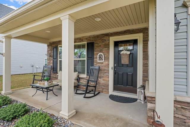 view of exterior entry with a porch and stone siding