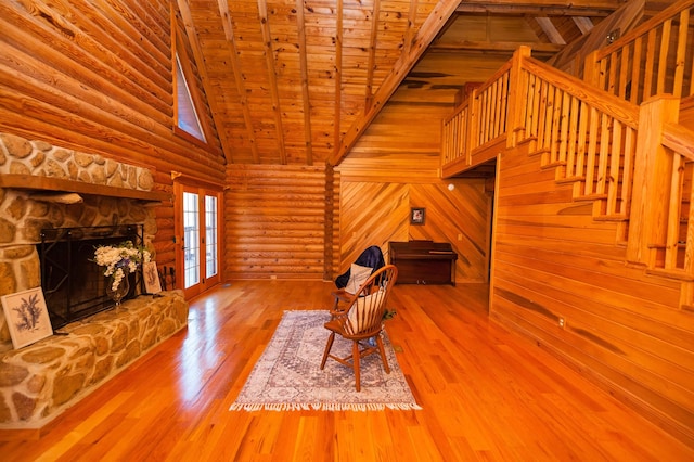 144 Lakeshore, Chesnee, SC 29323 - unfurnished living room with a stone fireplace, rustic walls, wood ceiling, wood finished floors, and stairs