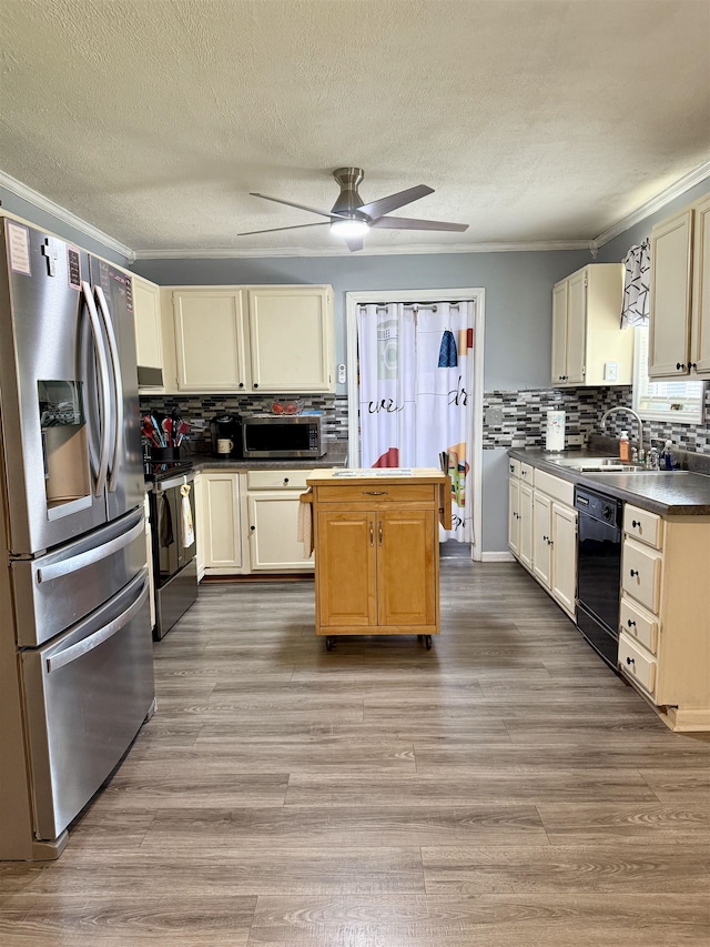 kitchen featuring stainless steel appliances, a sink, ceiling fan, crown molding, and backsplash