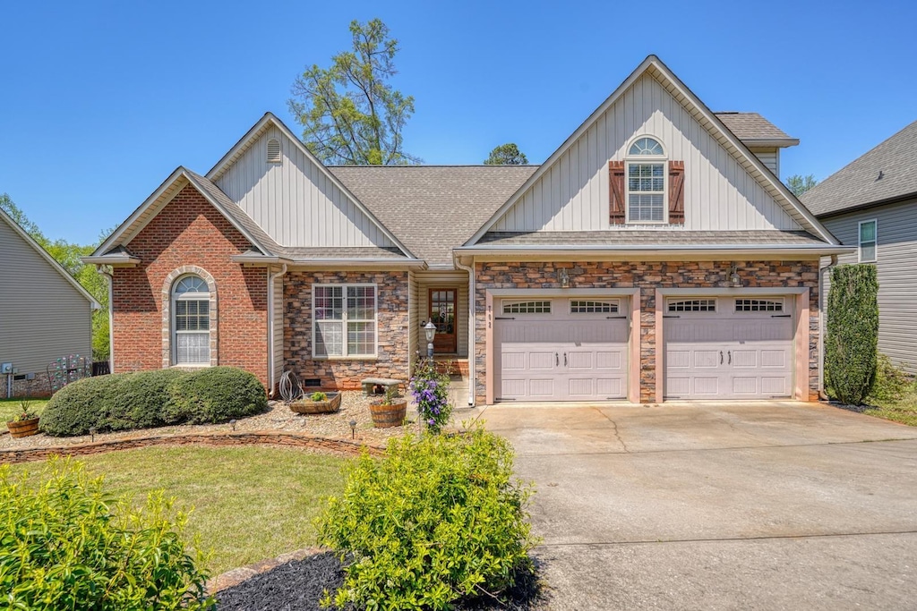 craftsman-style home featuring roof with shingles, board and batten siding, concrete driveway, and a front lawn