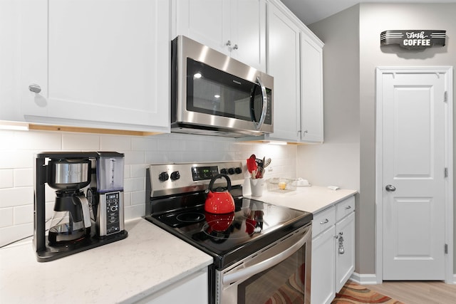 122 Aleppo, Greer, SC 29651 - kitchen featuring light stone countertops, white cabinets, appliances with stainless steel finishes, light wood finished floors, and backsplash
