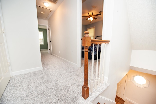 hallway featuring attic access, baseboards, carpet flooring, and an upstairs landing