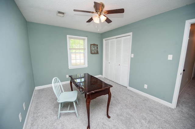 carpeted office space featuring a textured ceiling, baseboards, and a ceiling fan
