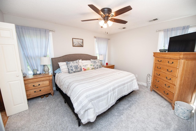 bedroom featuring visible vents, multiple windows, and light carpet