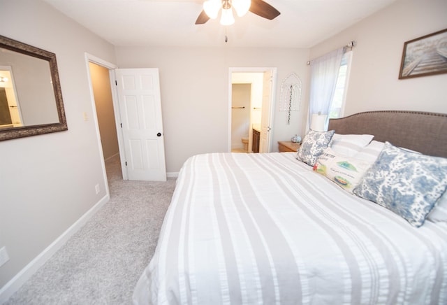 carpeted bedroom with ensuite bathroom, baseboards, and a ceiling fan