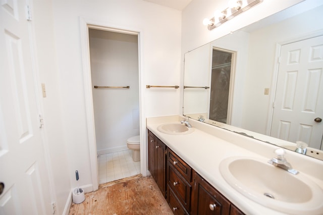 bathroom featuring double vanity, baseboards, a sink, and toilet