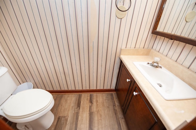 bathroom with toilet, wood finished floors, vanity, and baseboards