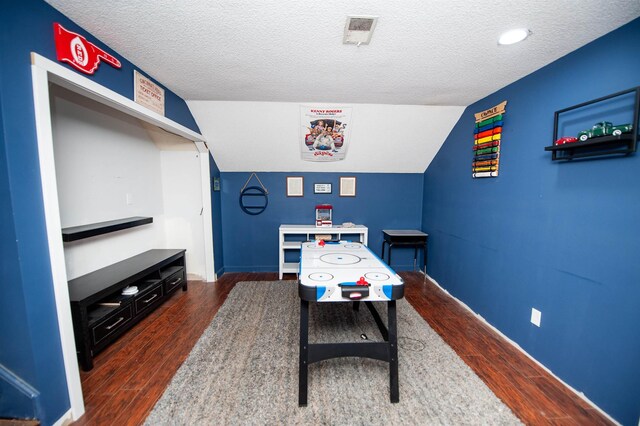 game room with visible vents, vaulted ceiling, wood finished floors, and a textured ceiling
