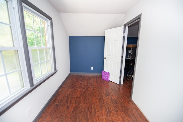 interior space with dark wood-style floors, baseboards, and lofted ceiling