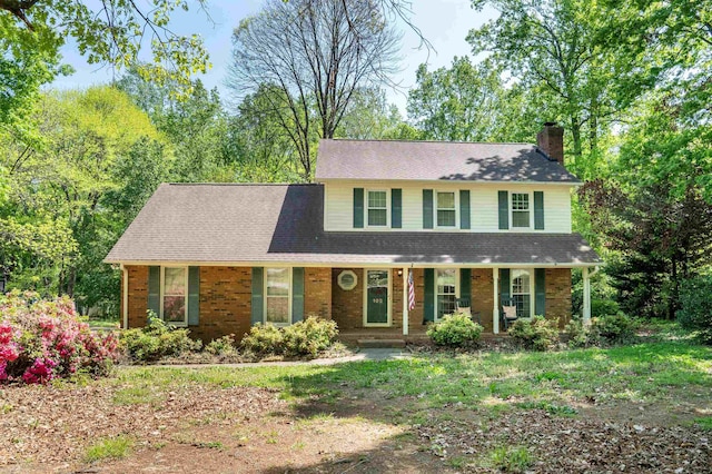 view of front of home with a porch, brick siding, and a chimney