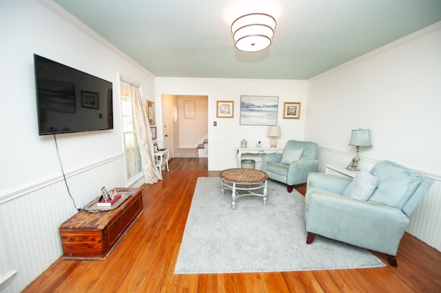 living area with stairway, ornamental molding, and wood finished floors