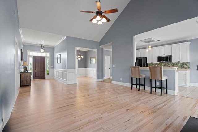 208 W Coosaw, Roebuck, SC 29376 - living room featuring high vaulted ceiling, light wood finished floors, ceiling fan with notable chandelier, and ornamental molding