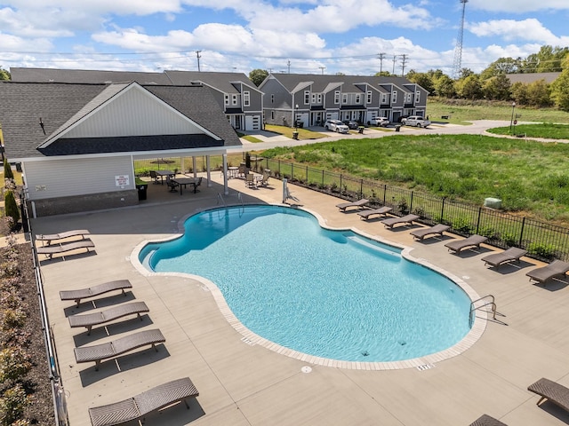 pool with a residential view, a patio area, a lawn, and fence
