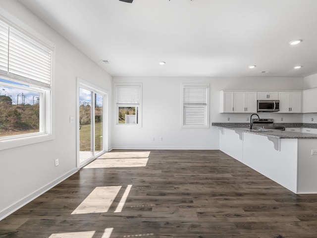 kitchen featuring white cabinets, recessed lighting, a kitchen breakfast bar, stainless steel appliances, and baseboards