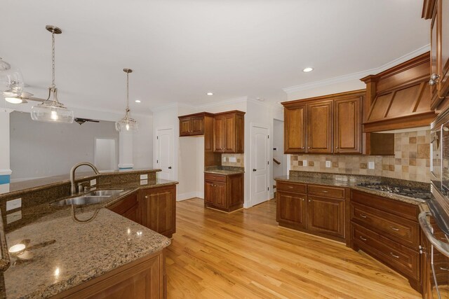 6 Pepper Bush, Greer, SC 29651 - kitchen with light wood finished floors, brown cabinetry, a sink, stainless steel gas cooktop, and tasteful backsplash