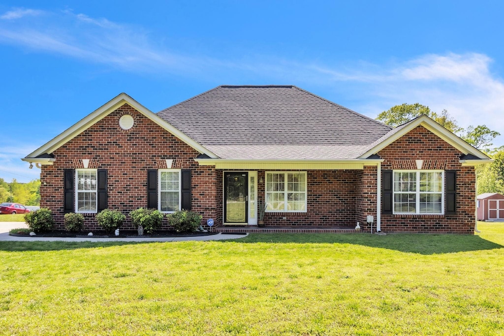 ranch-style home with brick siding, a shingled roof, and a front yard
