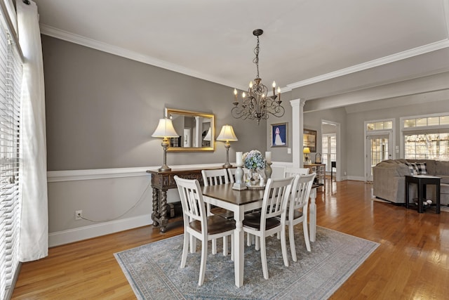 dining room with an inviting chandelier, crown molding, wood finished floors, and baseboards
