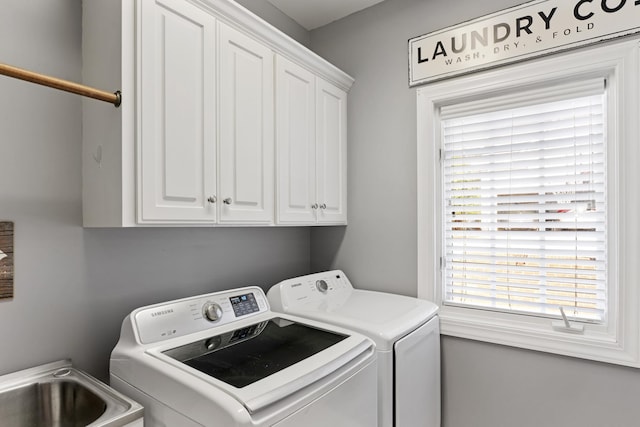 laundry area featuring plenty of natural light, washer and clothes dryer, and cabinet space