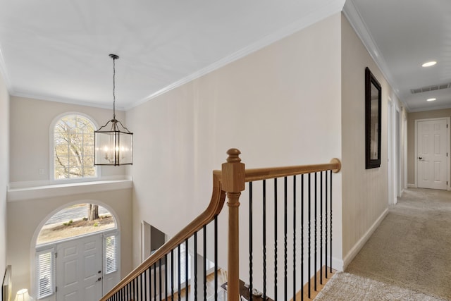 corridor featuring baseboards, a chandelier, an upstairs landing, crown molding, and carpet floors