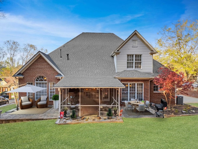 rear view of house with brick siding, a patio area, a sunroom, and a shingled roof