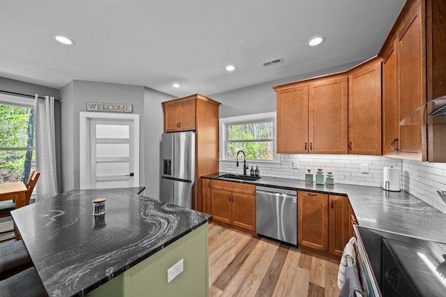 kitchen with a sink, decorative backsplash, stainless steel appliances, light wood-style flooring, and recessed lighting