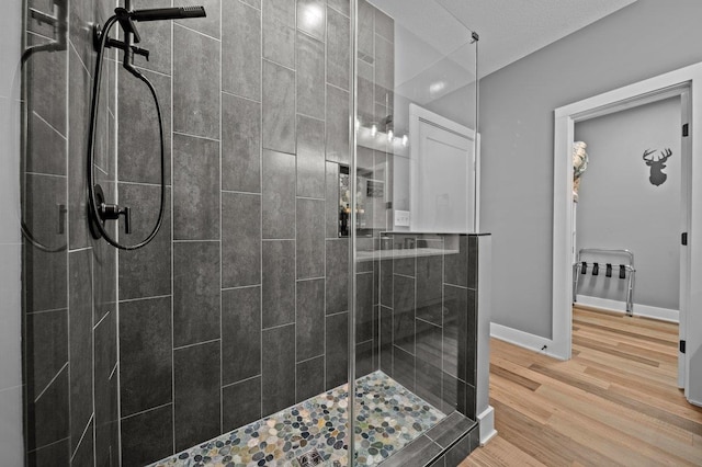 bathroom with baseboards, wood finished floors, and a shower stall