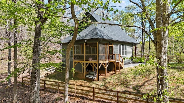back of property featuring fence, a shingled roof, a sunroom, and a deck
