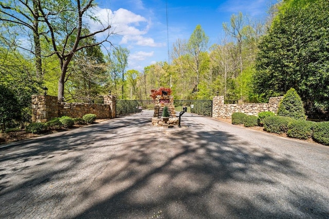 surrounding community featuring a gate, aphalt driveway, and fence