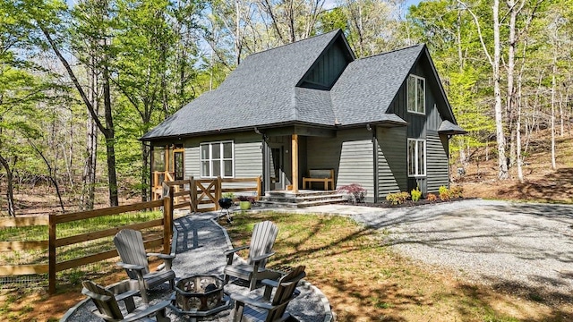 chalet / cabin featuring board and batten siding, roof with shingles, an outdoor fire pit, and fence