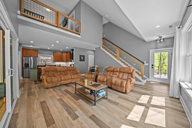 living room with light wood finished floors, high vaulted ceiling, recessed lighting, and stairway