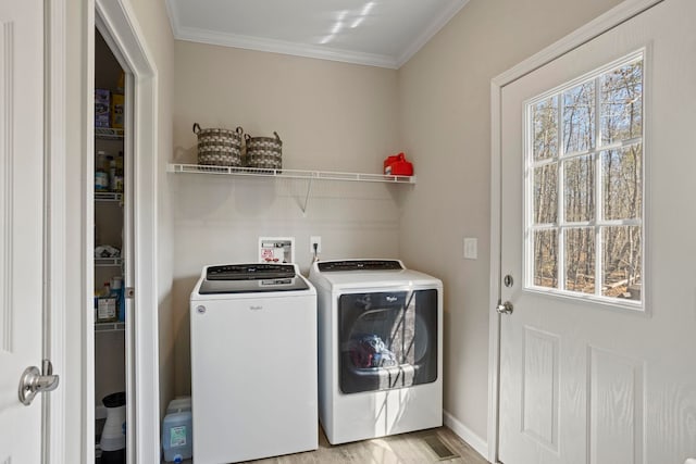 clothes washing area featuring light wood finished floors, baseboards, separate washer and dryer, laundry area, and ornamental molding