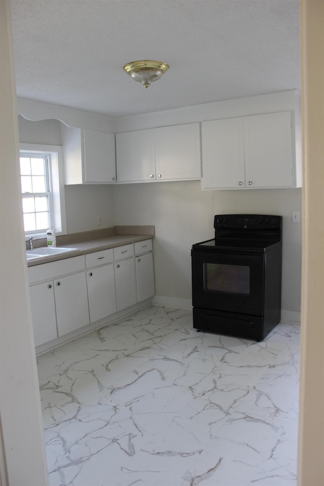 kitchen featuring marble finish floor, a sink, white cabinetry, and electric range