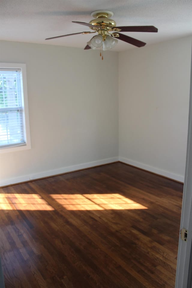 empty room featuring dark wood-type flooring, baseboards, and ceiling fan