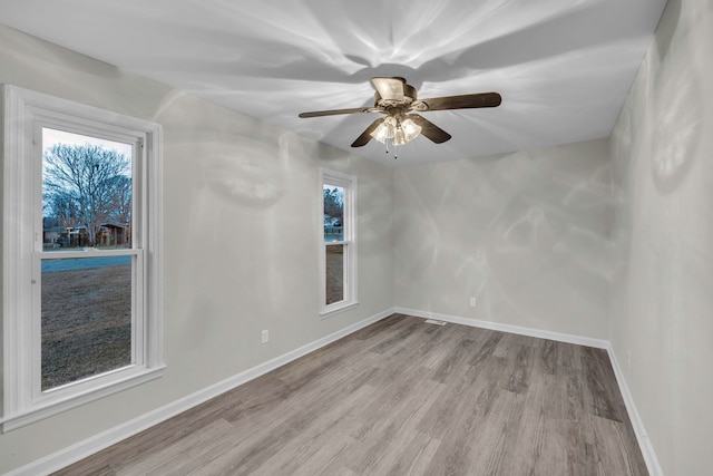empty room featuring light wood-style floors, a ceiling fan, and baseboards