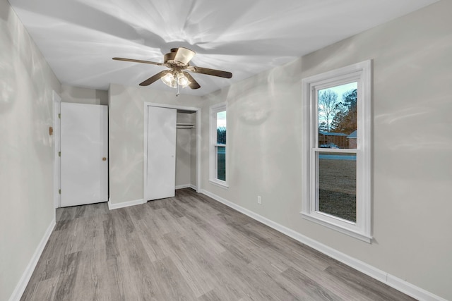 unfurnished bedroom featuring wood finished floors, a closet, baseboards, and ceiling fan